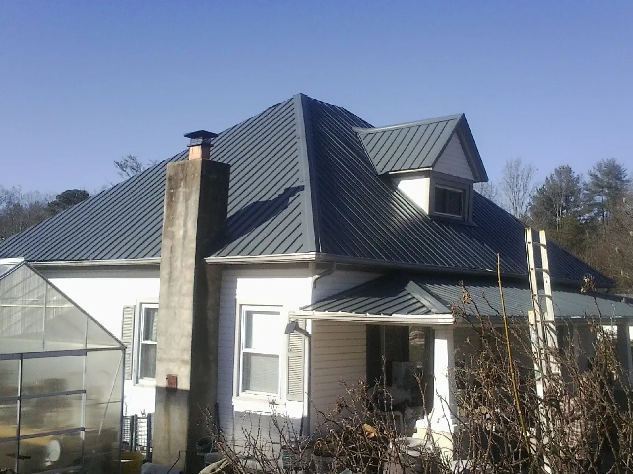 Dark blue standing seam metal roof on a white farmhouse with dormer — Slate & Tile Roof Repair by Roofing Brothers in Bakersfield