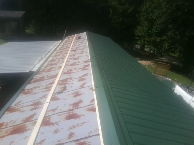 Old rusted panels beside newly installed green metal roofing — Wind Damage Roof Repair by Roofing Brothers in Bakersfield