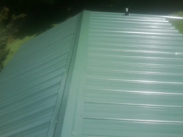 New green metal panels meeting at the ridge of a roof — Flat Roof Repair work by our crew in Bakersfield