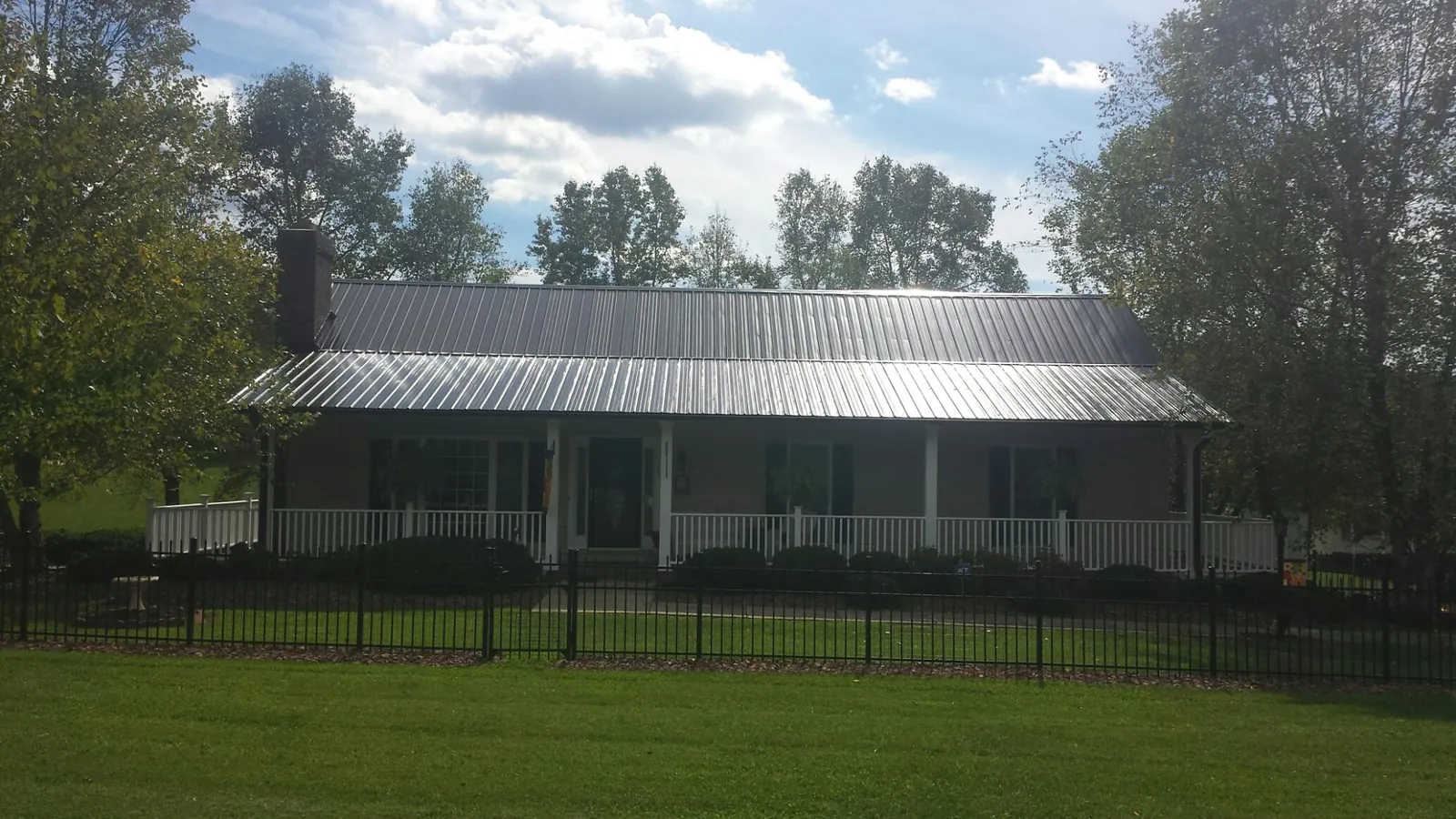 Gray metal roof on a brick ranch with a full width front porch — Gutter Guard Installation work by our crew in Bakersfield