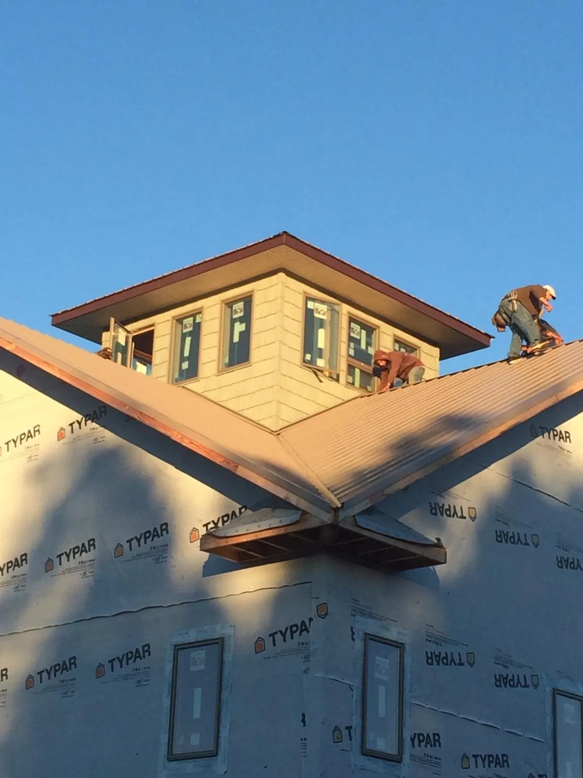 Roofers working around a rooftop cupola on a new metal roof at sunset — Roof Waterproofing in Bakersfield by Roofing Brothers